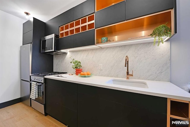 kitchen with decorative backsplash, sink, stainless steel appliances, and light hardwood / wood-style flooring