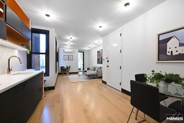 interior space with light hardwood / wood-style flooring, an AC wall unit, and sink