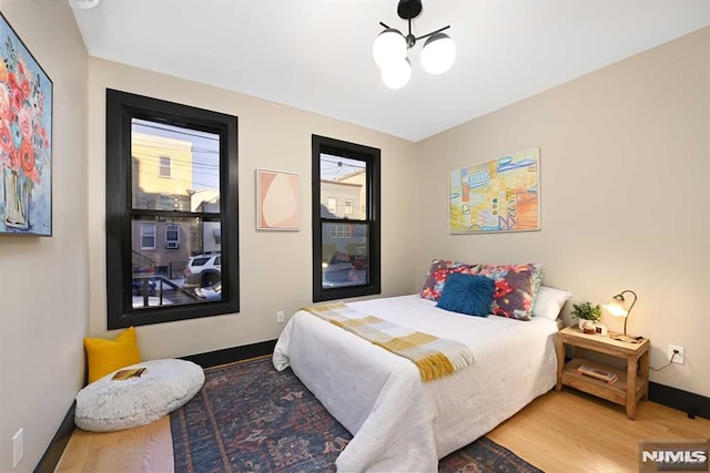 bedroom with wood-type flooring and an inviting chandelier