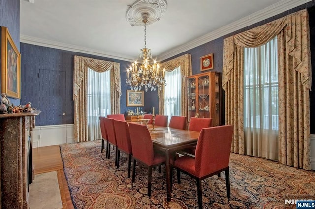 dining room with crown molding, a notable chandelier, a wainscoted wall, and wallpapered walls