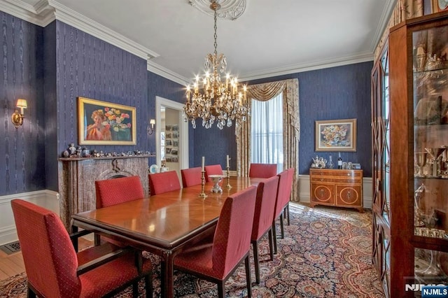 dining space with a notable chandelier, wainscoting, crown molding, and wallpapered walls