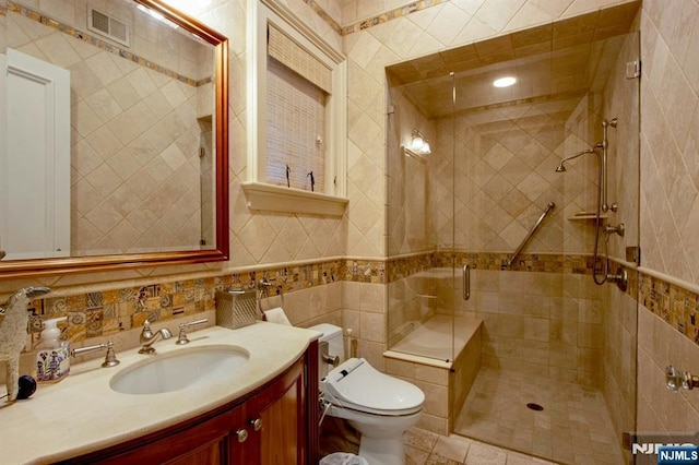 bathroom featuring a stall shower, tile walls, toilet, visible vents, and vanity
