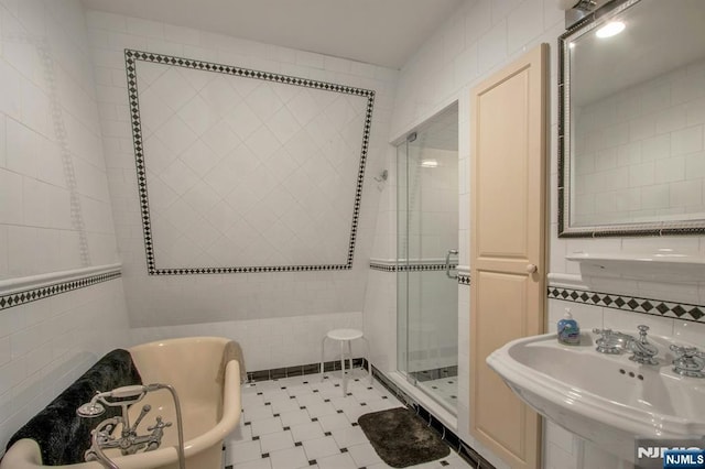 full bathroom with a stall shower, tile walls, a sink, and a freestanding tub