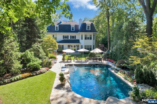 pool with a yard and a patio area
