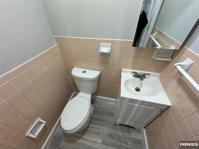 bathroom featuring hardwood / wood-style flooring, vanity, tile walls, and toilet