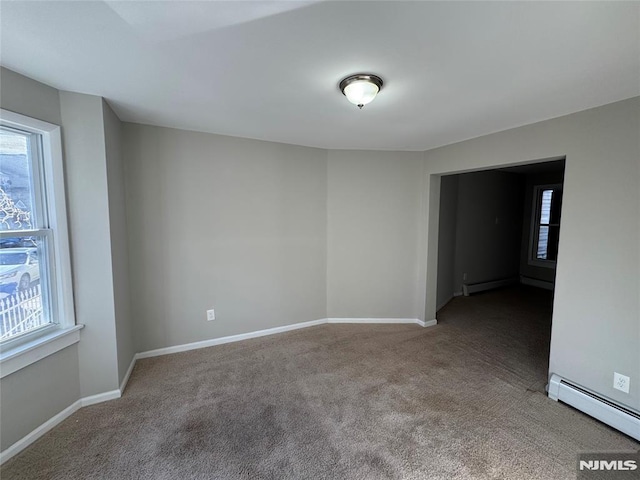 carpeted empty room with a baseboard heating unit