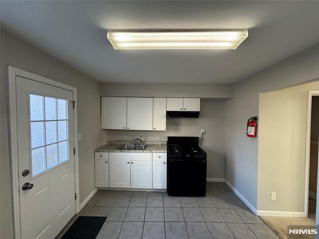 kitchen featuring white cabinetry, sink, black gas range oven, stone countertops, and light tile patterned floors