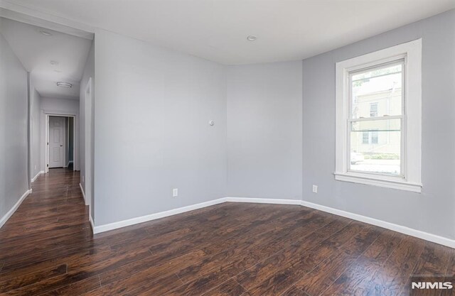 empty room featuring a healthy amount of sunlight and dark hardwood / wood-style floors