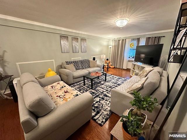 living room with ornamental molding and dark wood-type flooring