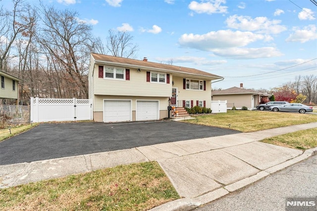 raised ranch featuring a garage and a front yard