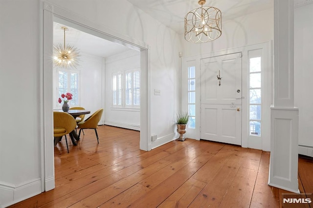 entrance foyer with a baseboard heating unit, light wood-type flooring, and a notable chandelier