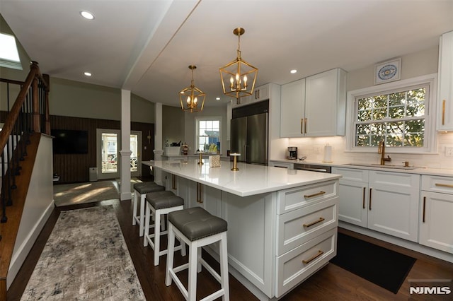 kitchen with white cabinets, high end refrigerator, a kitchen island, and a breakfast bar area