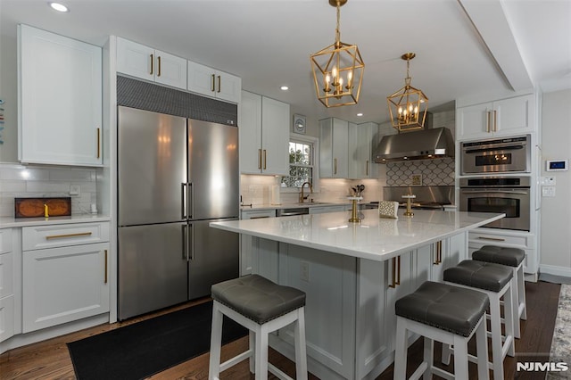 kitchen with a center island, built in fridge, decorative backsplash, range hood, and white cabinetry