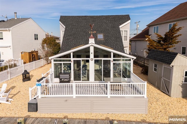 rear view of house featuring a wooden deck, a sunroom, and a storage shed