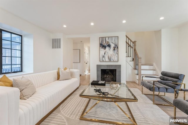 living room with a tile fireplace and light hardwood / wood-style floors