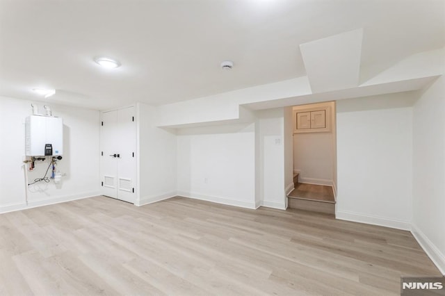 basement featuring light hardwood / wood-style flooring and water heater