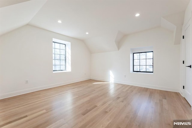 additional living space featuring light wood-type flooring and vaulted ceiling