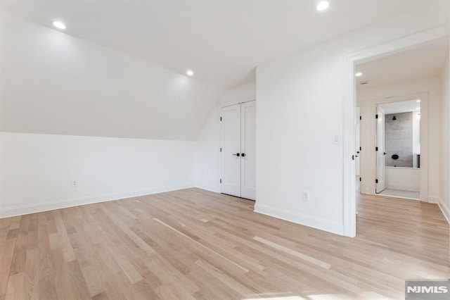 bonus room featuring light wood-type flooring and vaulted ceiling