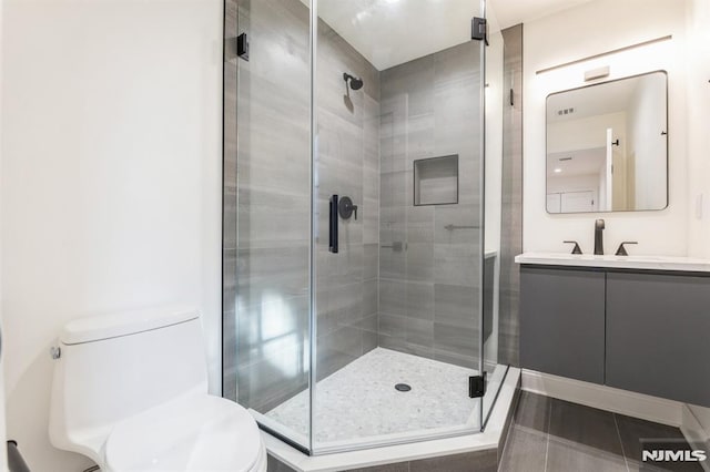 bathroom with an enclosed shower, vanity, toilet, and tile patterned flooring