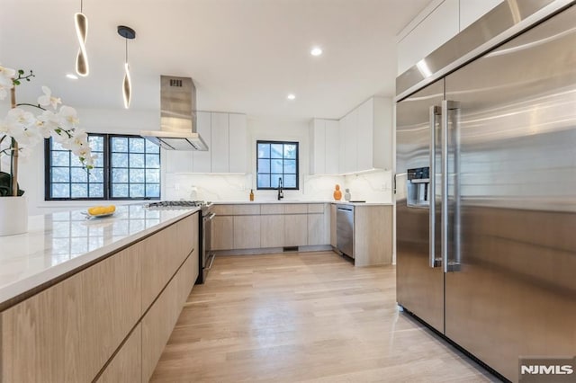 kitchen with white cabinetry, sink, stainless steel appliances, pendant lighting, and extractor fan