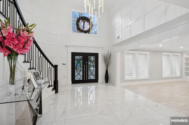 entryway featuring a chandelier, french doors, a wealth of natural light, and a high ceiling