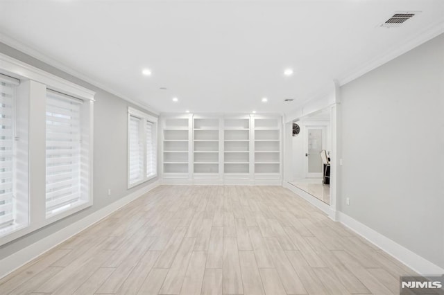 empty room featuring light hardwood / wood-style flooring, built in features, and ornamental molding