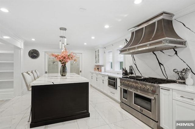 kitchen with appliances with stainless steel finishes, premium range hood, ornamental molding, white cabinets, and a kitchen island