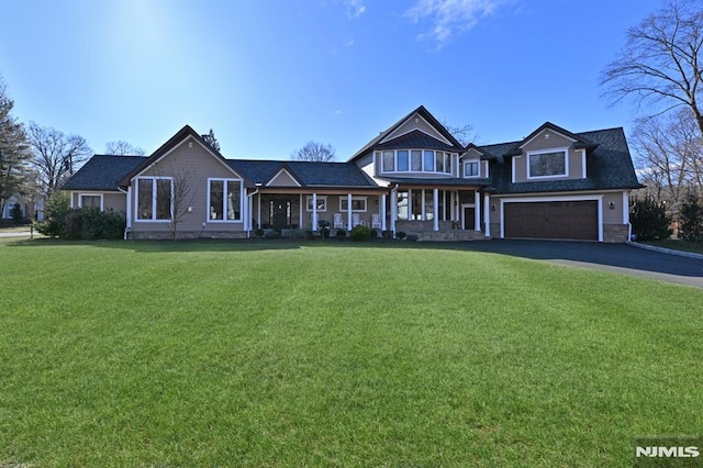 view of front of property featuring a porch, a garage, and a front lawn