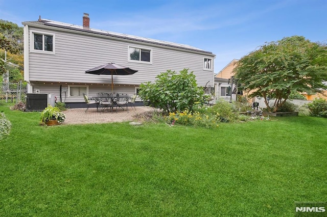 back of house featuring solar panels, a patio, cooling unit, and a lawn