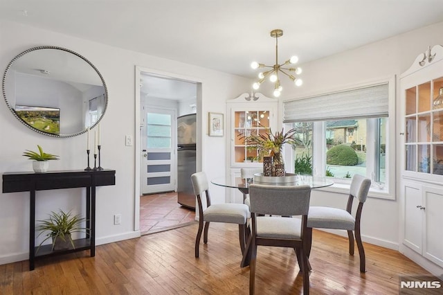 dining space with a notable chandelier, a healthy amount of sunlight, and hardwood / wood-style flooring