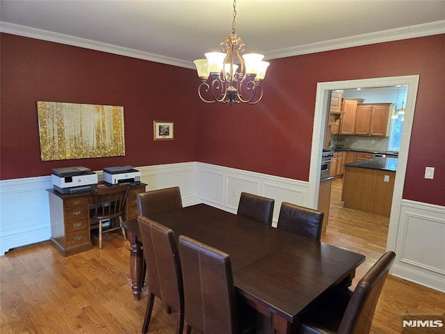 dining area with crown molding, light wood-type flooring, and a chandelier