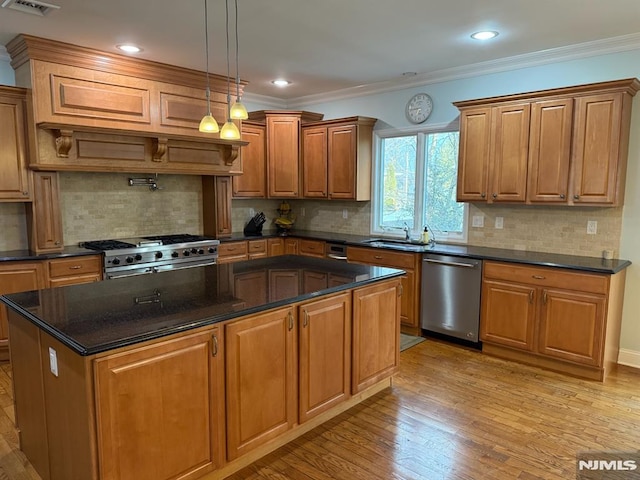 kitchen featuring crown molding, appliances with stainless steel finishes, sink, decorative light fixtures, and decorative backsplash