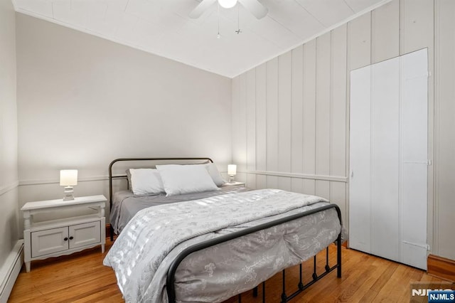 bedroom featuring a baseboard radiator, ceiling fan, and light wood-type flooring