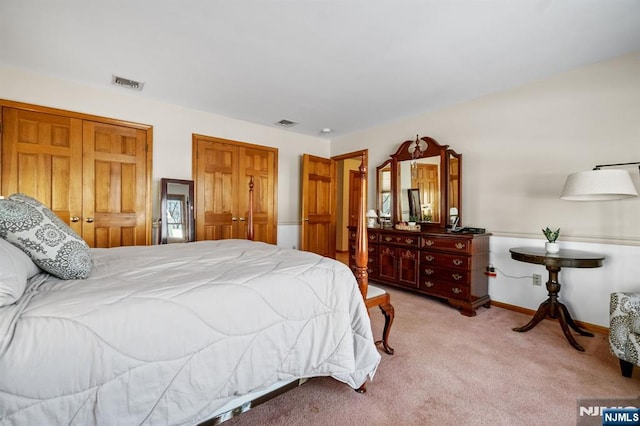 bedroom featuring multiple closets and light carpet