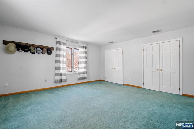 unfurnished bedroom featuring carpet floors and two closets