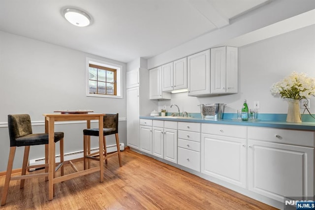 kitchen with white cabinetry, sink, light hardwood / wood-style floors, and a baseboard heating unit