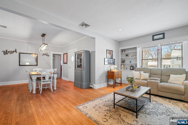 living room featuring hardwood / wood-style flooring, ornamental molding, and built in features