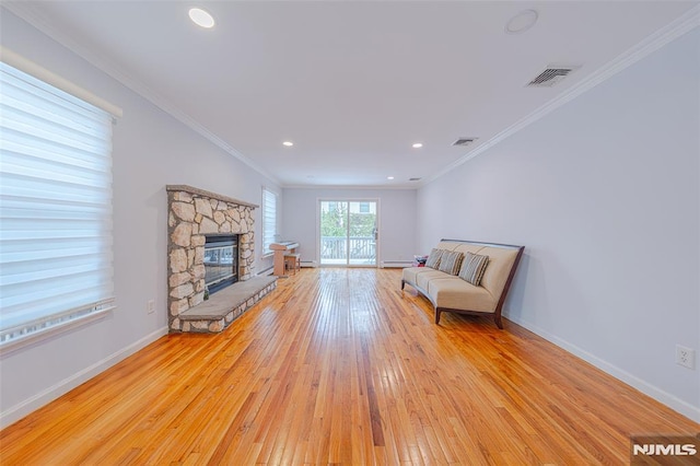 unfurnished room with light hardwood / wood-style flooring, ornamental molding, and a stone fireplace