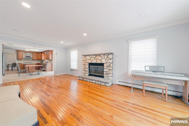 living room featuring a fireplace, crown molding, light hardwood / wood-style floors, and baseboard heating