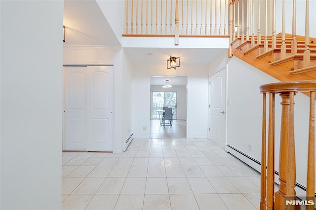 tiled foyer featuring a high ceiling, baseboard heating, and crown molding