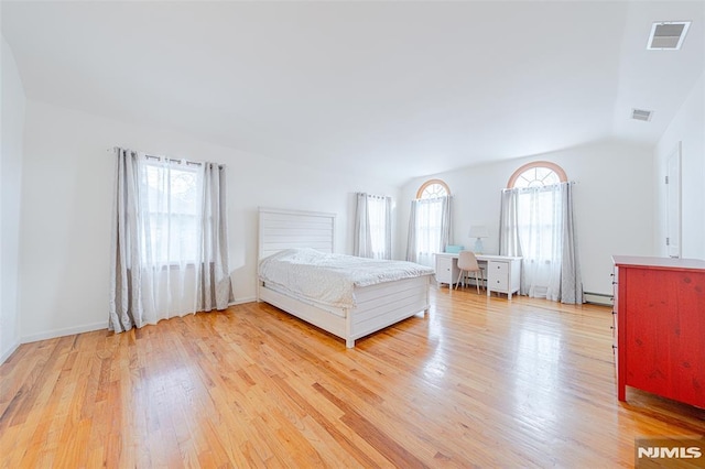 unfurnished bedroom featuring lofted ceiling, baseboard heating, multiple windows, and light hardwood / wood-style floors