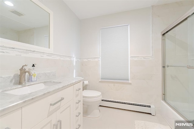 full bathroom featuring toilet, a baseboard radiator, bath / shower combo with glass door, tile walls, and vanity