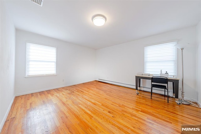 spare room featuring baseboard heating and wood-type flooring