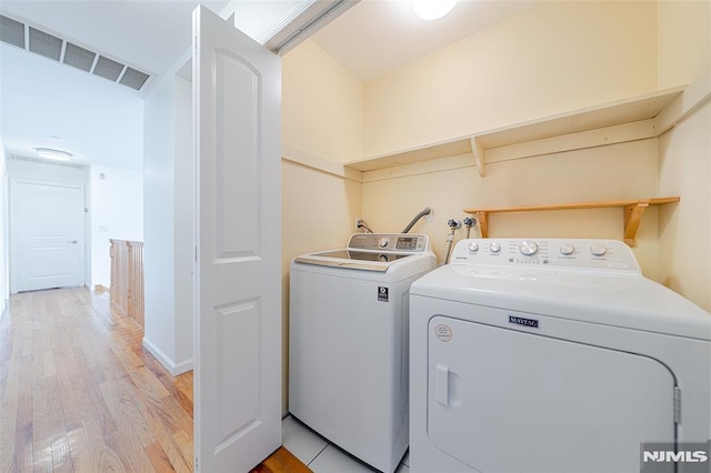 washroom with light wood-type flooring and separate washer and dryer