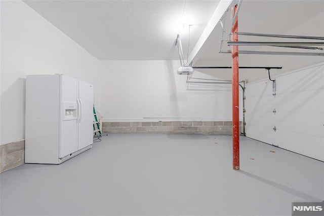 garage featuring white refrigerator with ice dispenser and a garage door opener