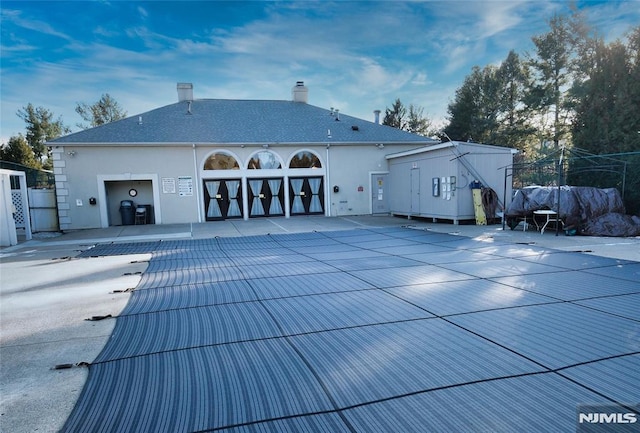 rear view of property with a patio area and a covered pool