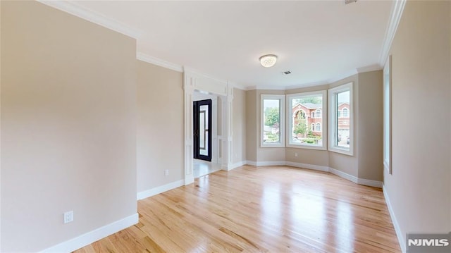 spare room featuring light hardwood / wood-style flooring and ornamental molding