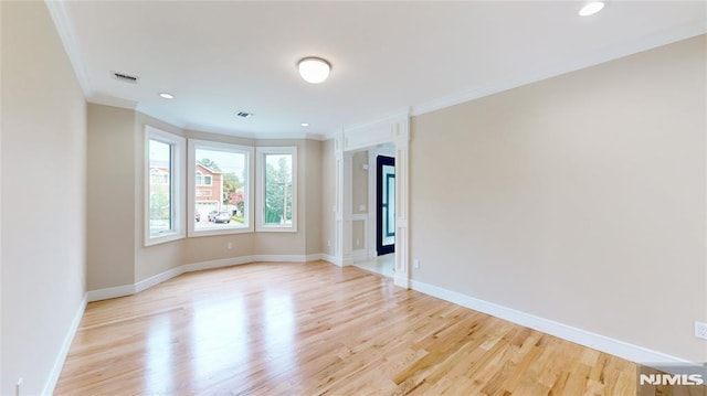 spare room with crown molding and light wood-type flooring