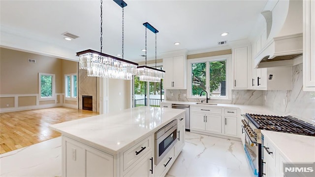 kitchen with appliances with stainless steel finishes, premium range hood, pendant lighting, white cabinetry, and a kitchen island