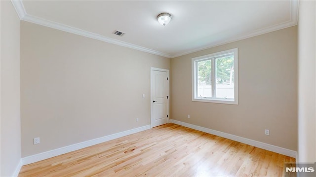 spare room with light hardwood / wood-style floors and crown molding